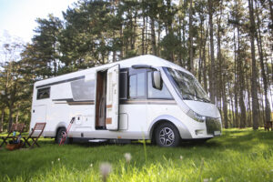 image of a white RV with the door open in front of trees.