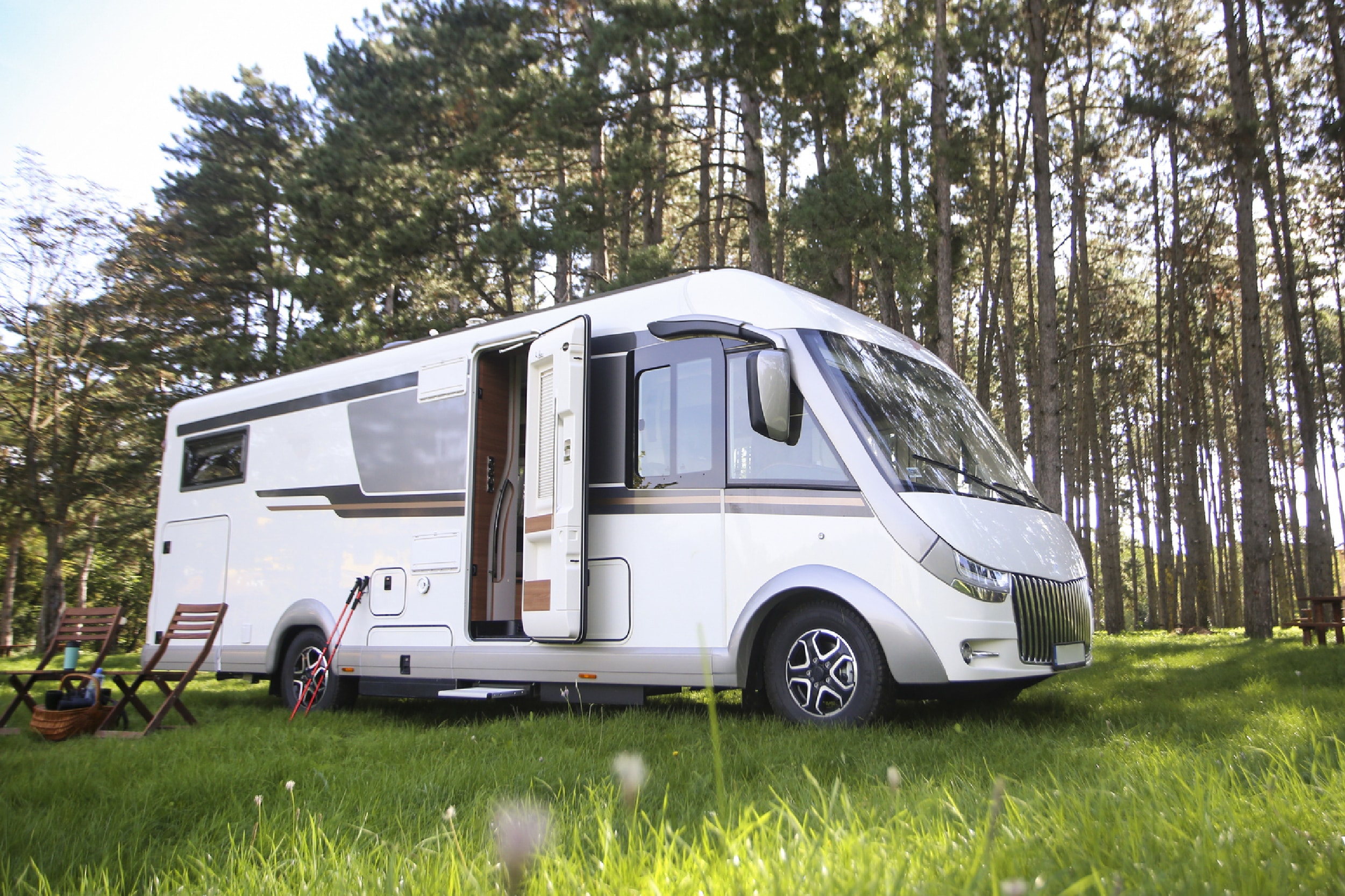 image of a white RV with the door open in front of trees.