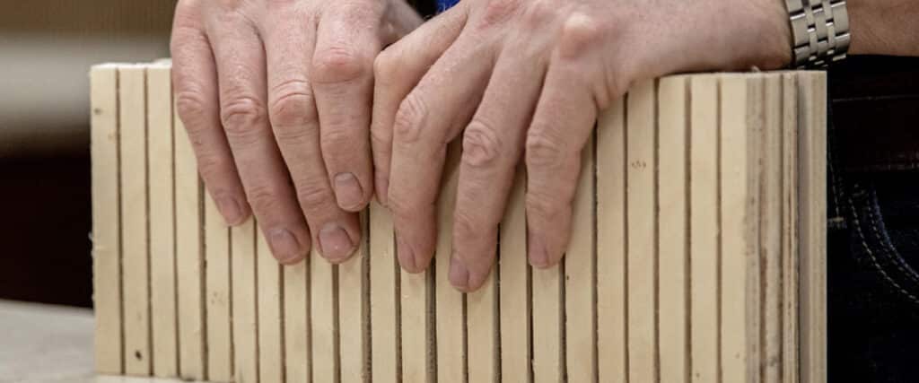 two hands holding a kerfkore panel with the kerfed side showing