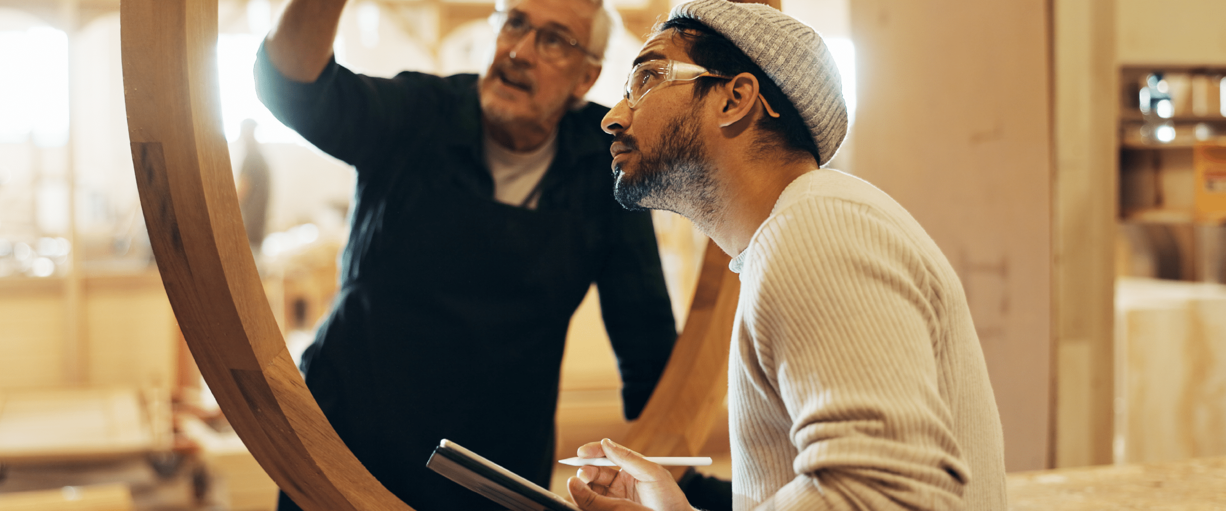 two men looking at a curved wood sculpture