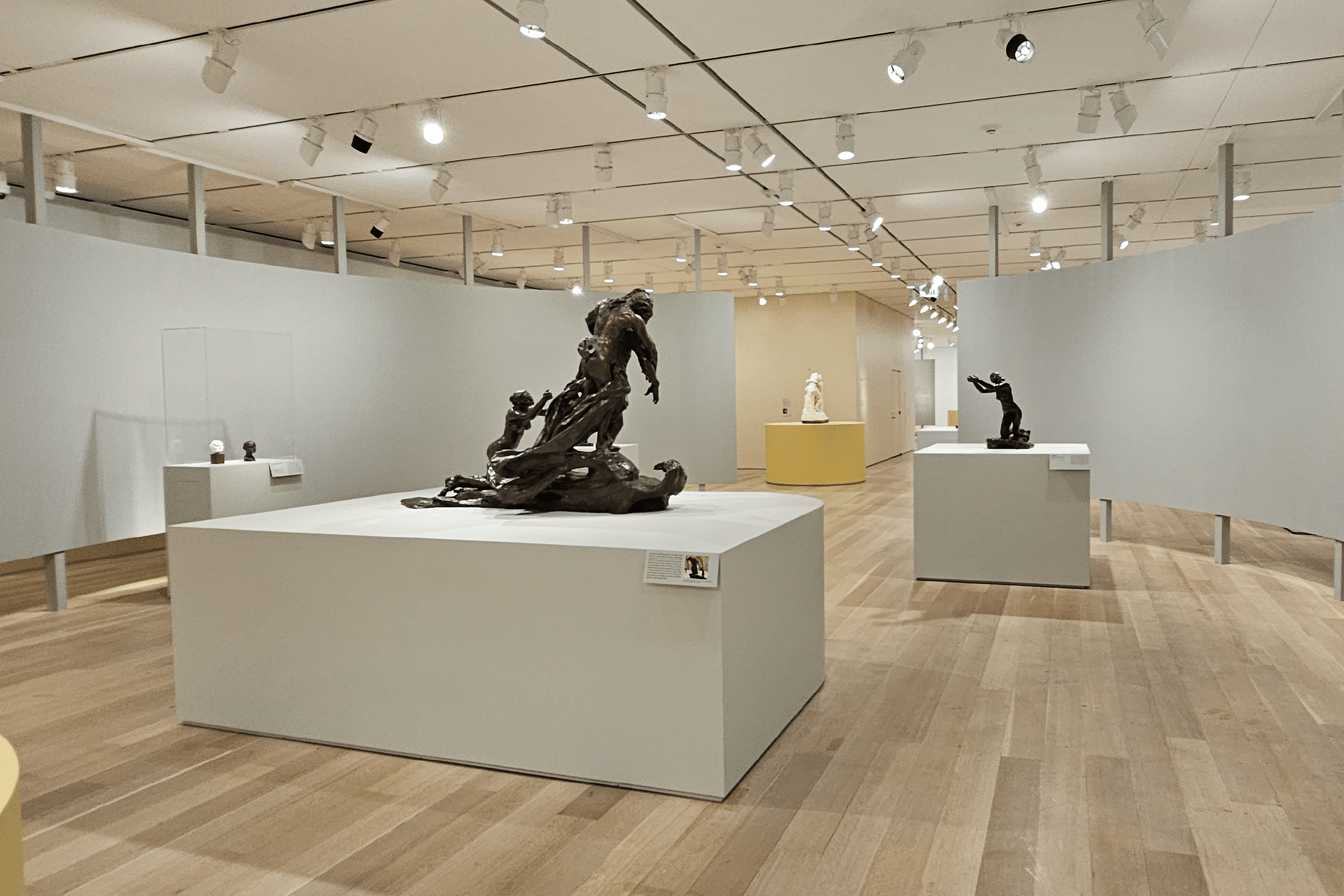 scultures one top of white boxes. in the back is a curved white panel made from kerfkore
